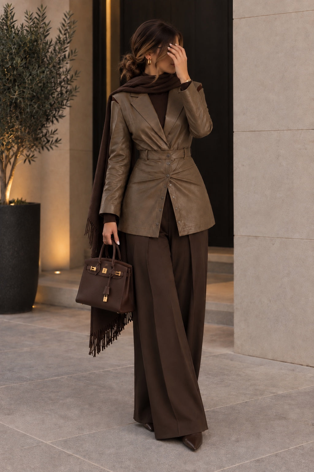 Woman wearing the OLIVARA khaki vegan leather belted blazer by Mateeno with chocolate wide-leg trousers and a brown fringed scarf